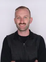 Headshot for Jay Johnson, a closeup image of a man in a black pullover smiling.