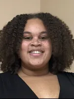 Headshot for Simone Harris, smiling in a black shirt